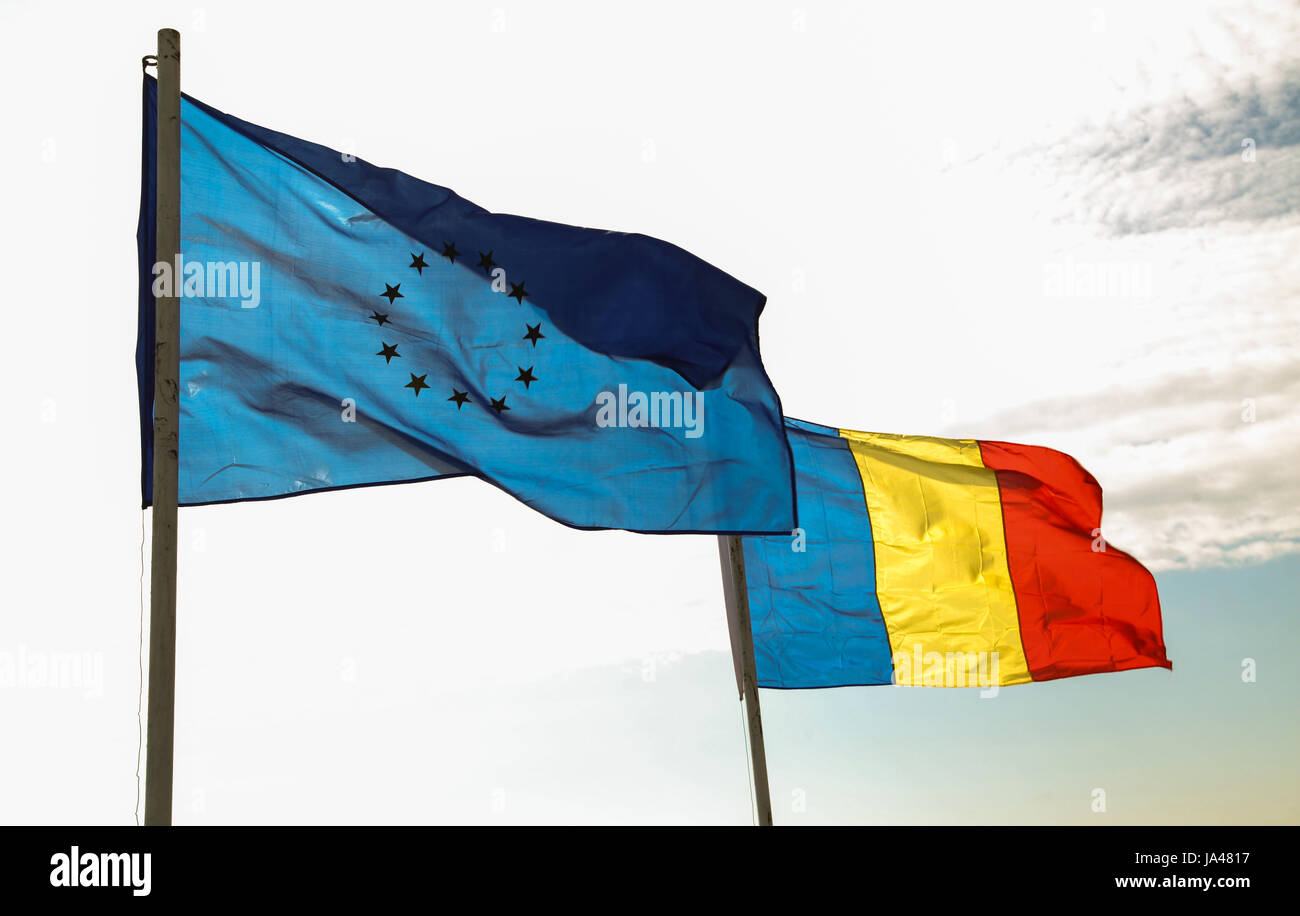 Counter light photo of EU and Romanian national flag waving on wind Stock Photo