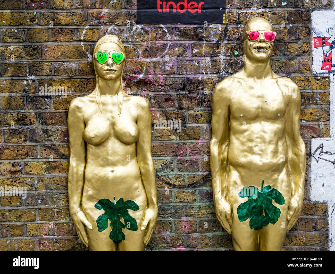 Gold painted male and female 3D relief statues by UrbanSolid, in London's popular Brick Lane in East London. Stock Photo