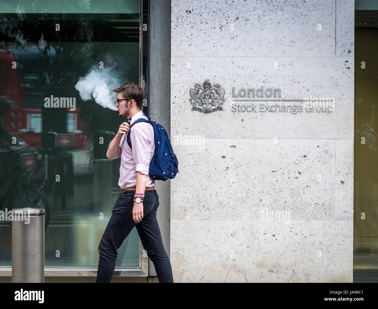 London Stock Exchange LSE - A city worker exhales vapour while passing the London Stock Exchange offices in the City of London, UK Stock Photo