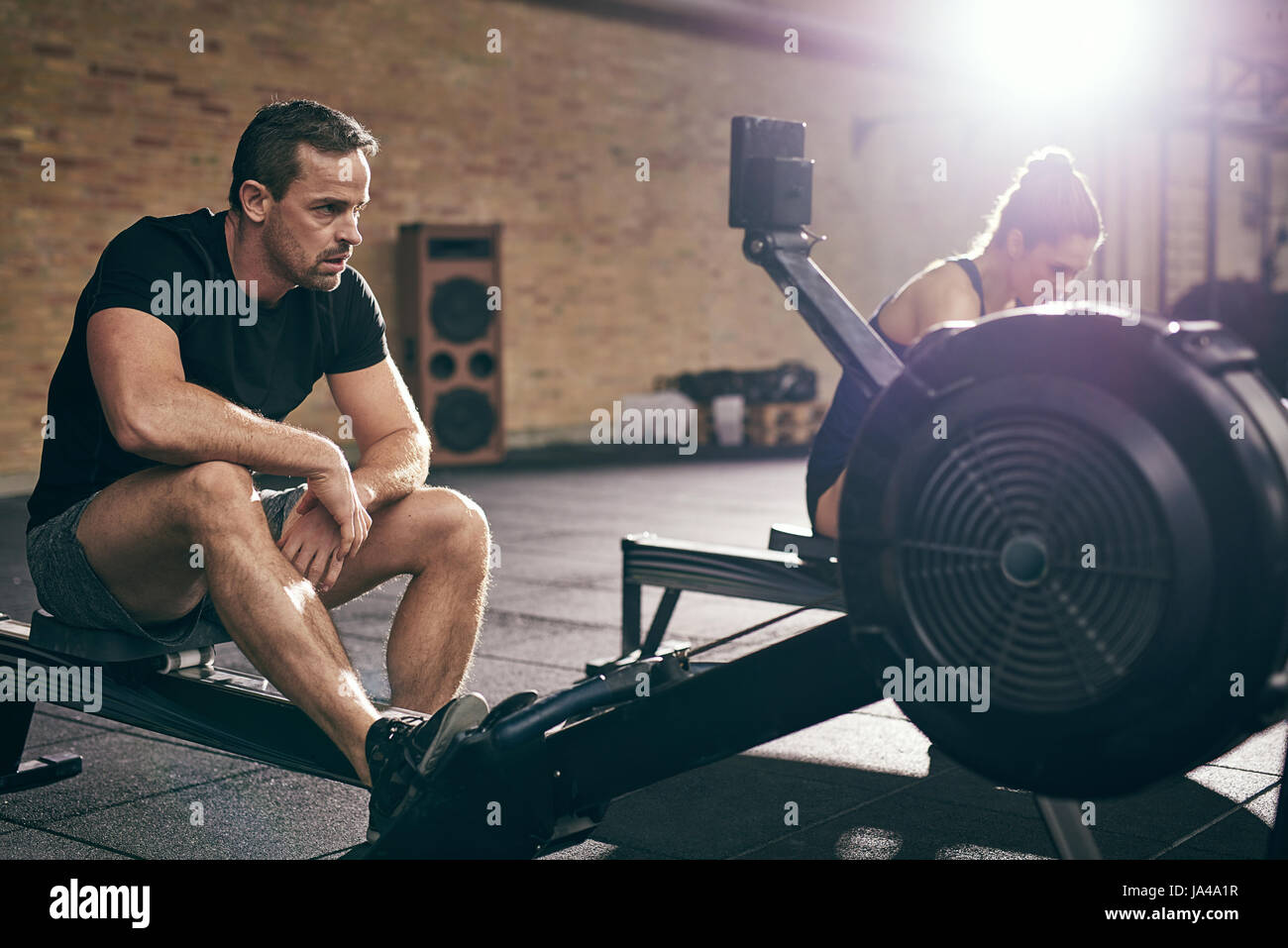 Two young athletic sportspeople exercising on body-builders in gym. Stock Photo