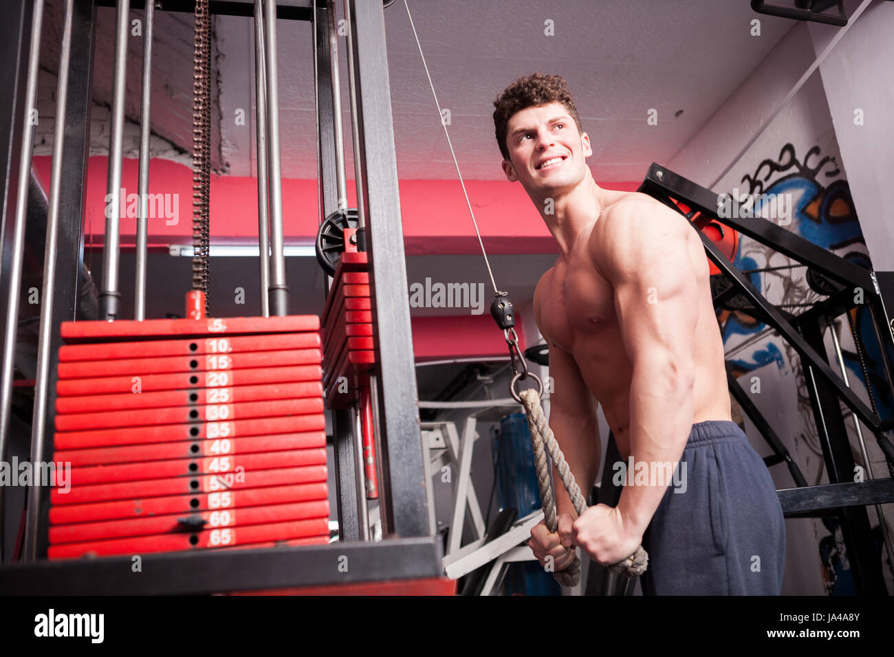 Muscular strong guy exercising in the gym. Lifting heavy weights