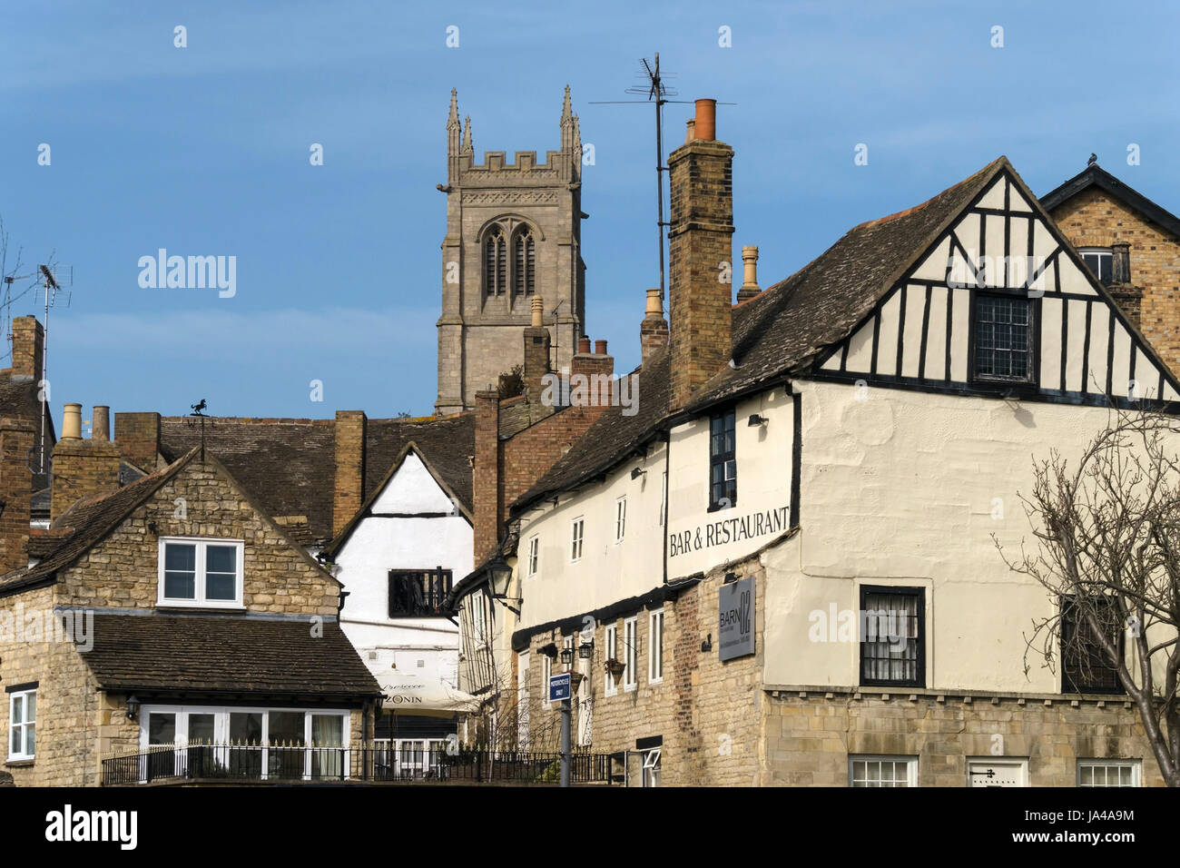 Old buildings, rooftops and St Johns Church Tower on a sunny day with blue sky above, Stamford, Lincolnshire, England, UK Stock Photo