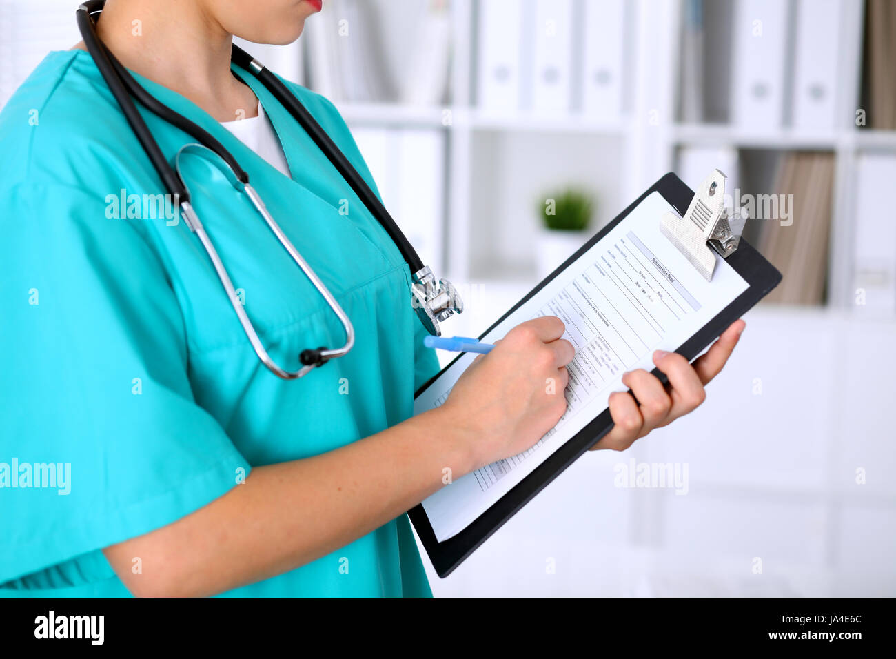 Close-up of a female doctor is filling out application form or medical ...