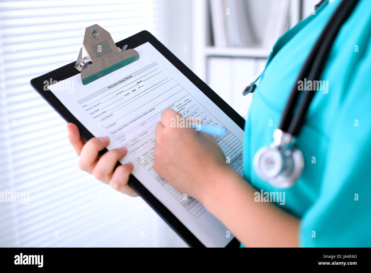 Close-up of a female doctor is filling out application form or medical ...