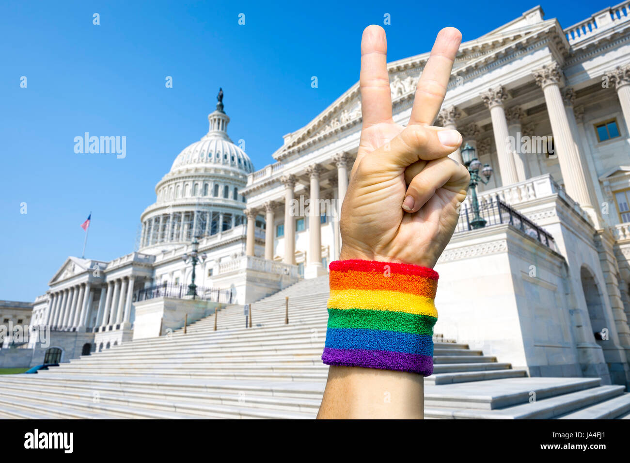 American hand wearing gay pride rainbow flag wristband holding up a peace sign gesture in front of the Capitol Building in Washington, DC, USA Stock Photo