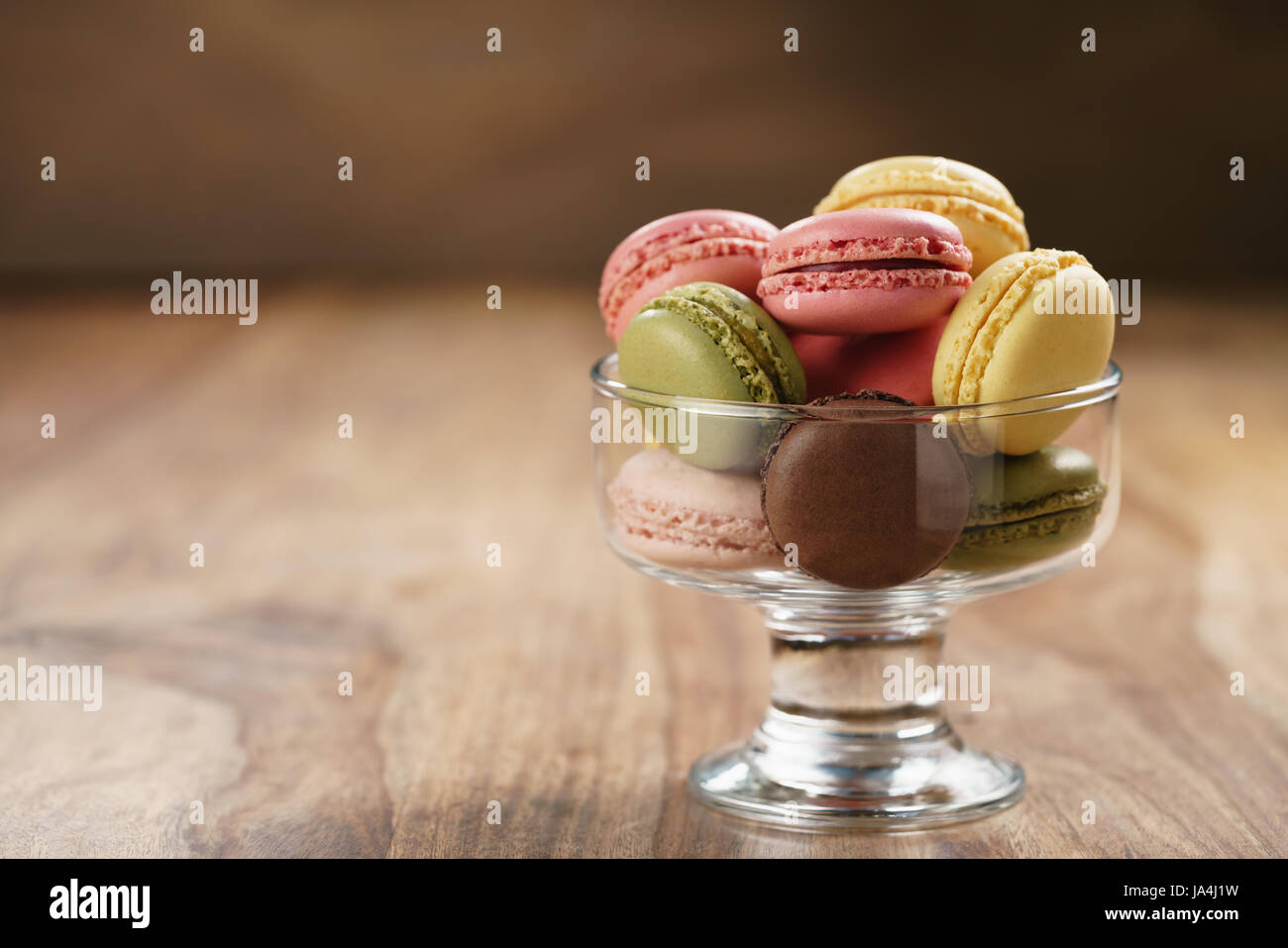 assorted macarons in glass bowl on wood table Stock Photo