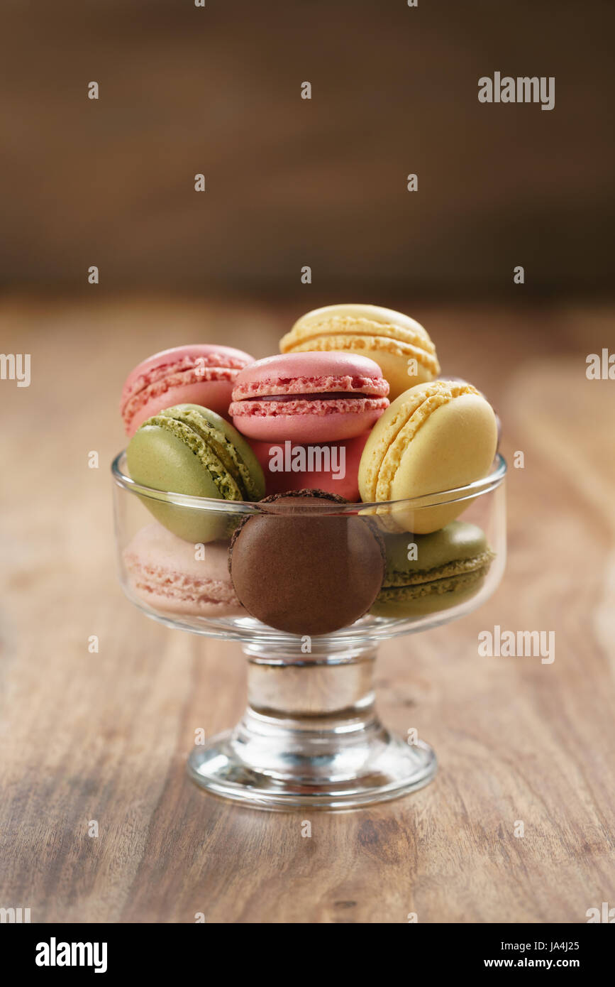 assorted macarons in glass bowl on wood table Stock Photo