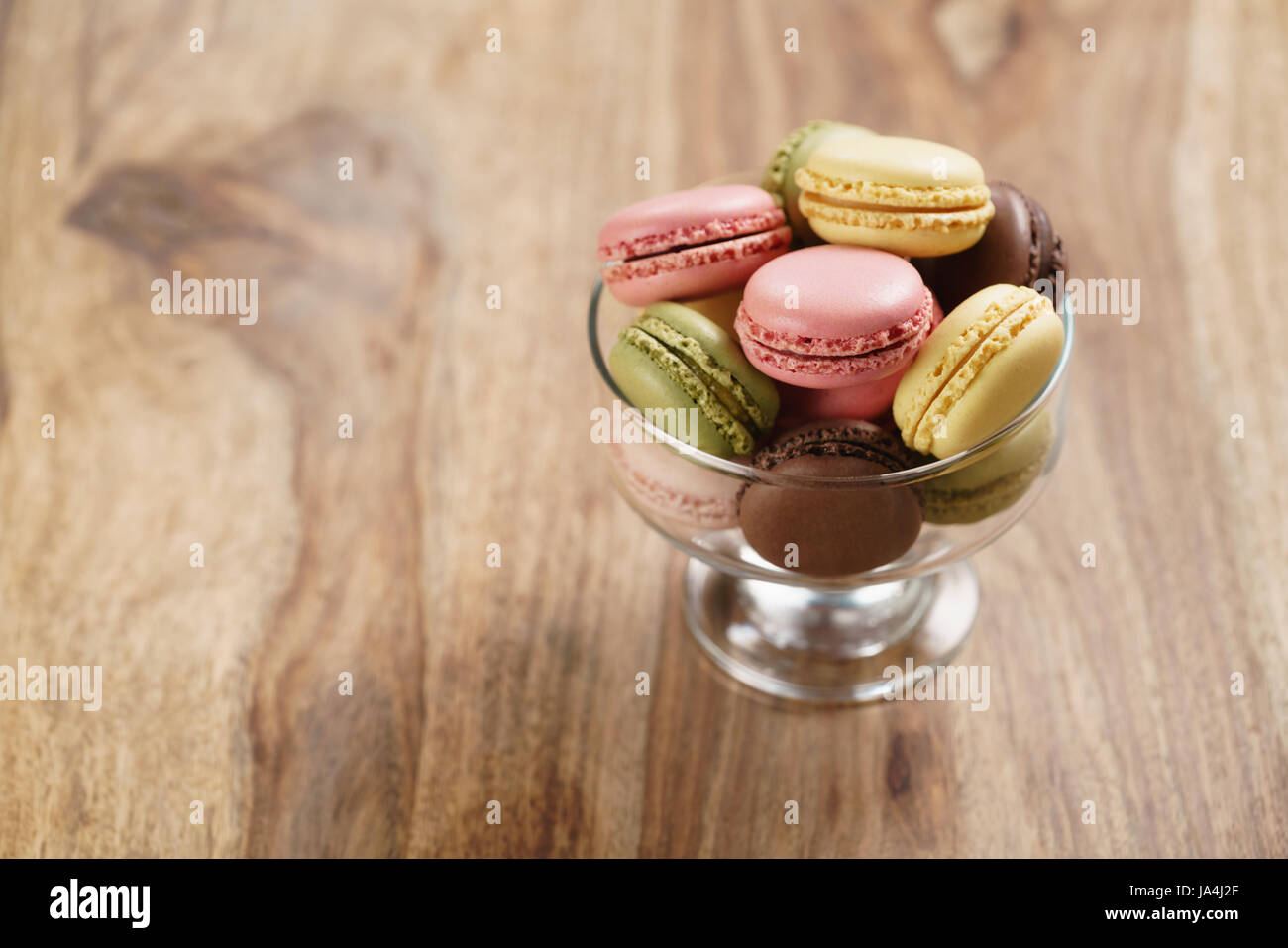 assorted macarons in glass bowl on wood table Stock Photo