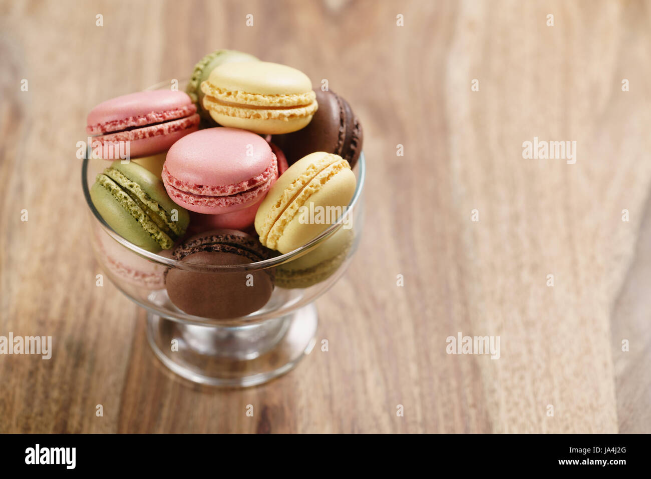 assorted macarons in glass bowl on wood table Stock Photo