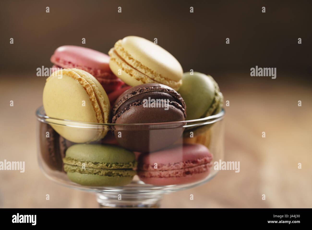 assorted macarons in glass bowl on wood table Stock Photo