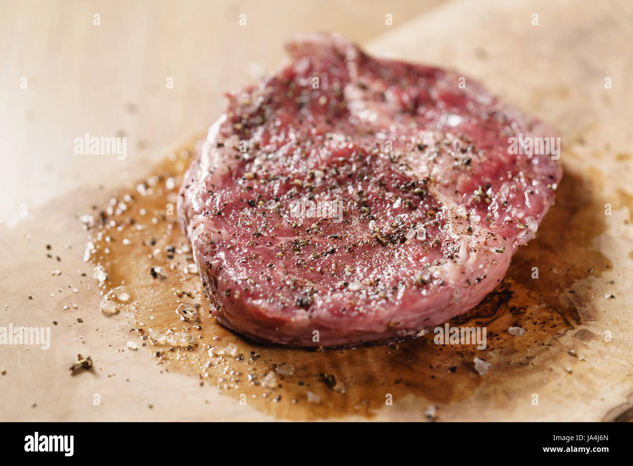 seasoned raw rib eye steak on board closeup Stock Photo