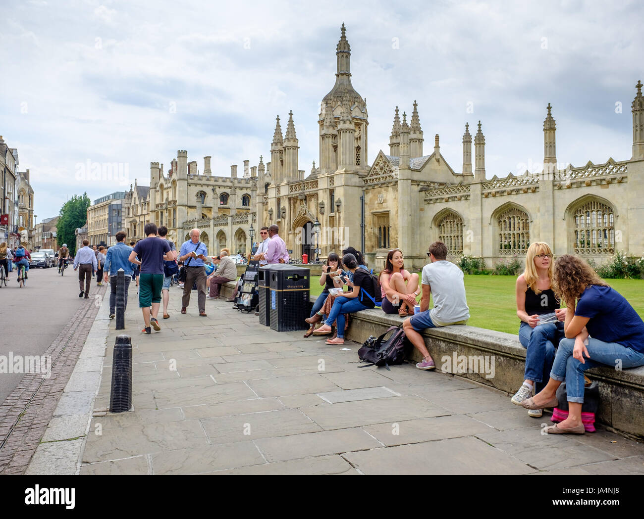 A variety of people sit on the low wall outside the front of King's college, university of Cambridge, England. Stock Photo