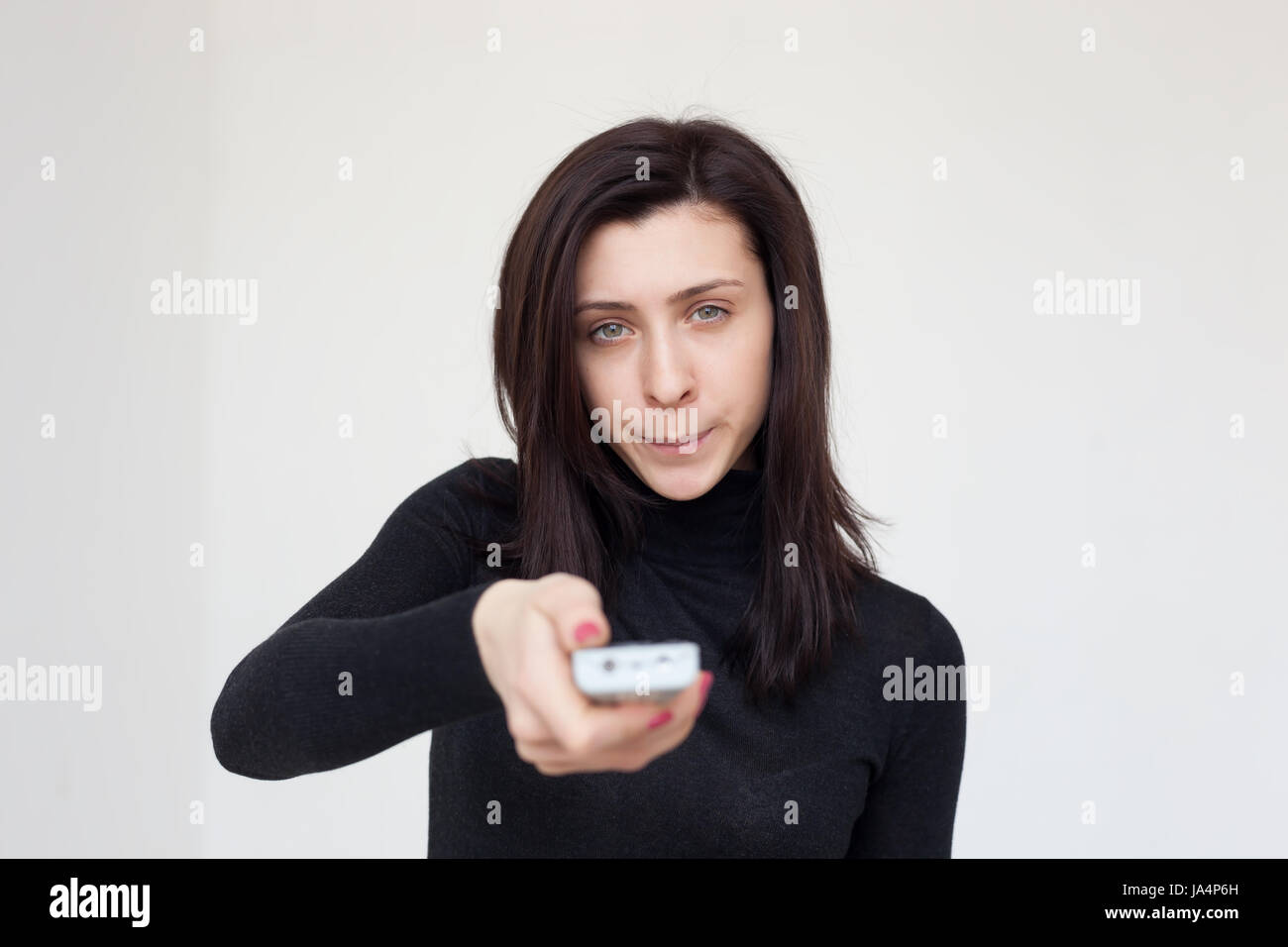 The dissatisfied girl switches the program on TV. She is angry with the information she saw Stock Photo