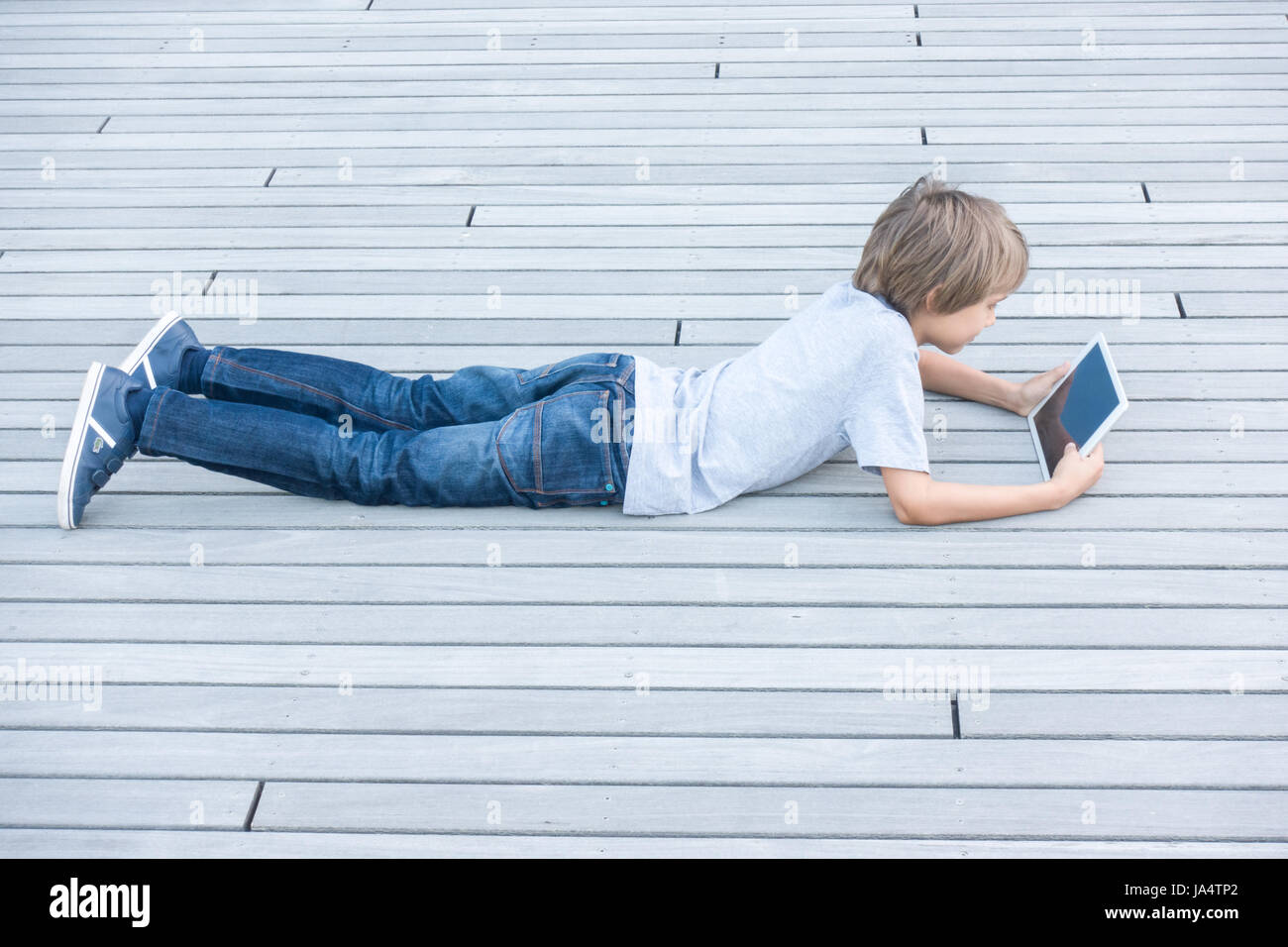 Boy with tablet computer lying on summer terrace Stock Photo - Alamy