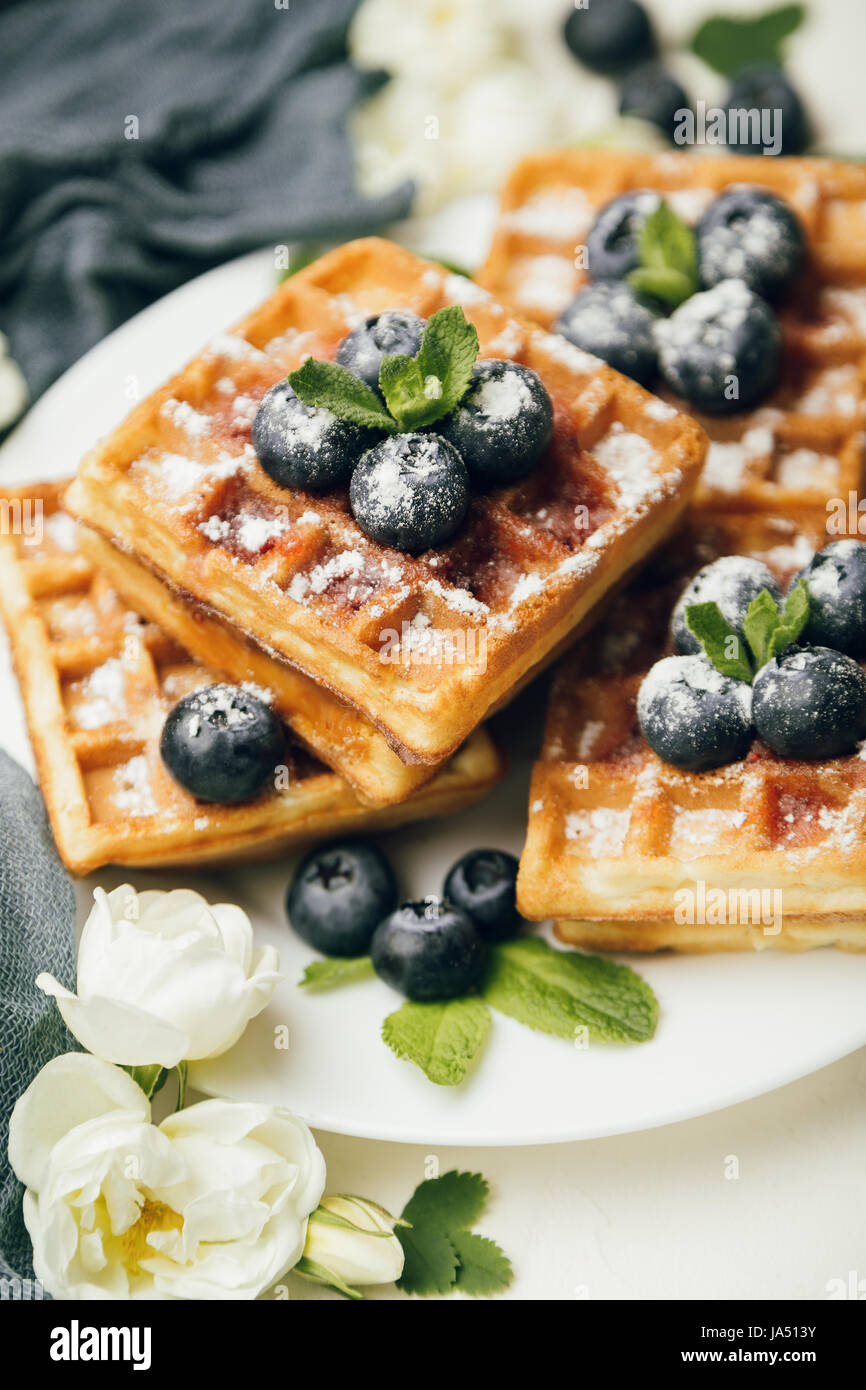 Belgian waffles with fresh blueberries and mint with white flowers on ...