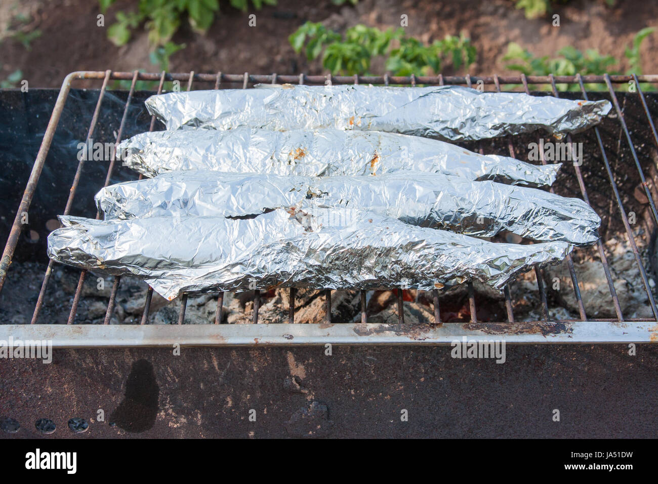 preparation of fish in foil on a grill Stock Photo Alamy