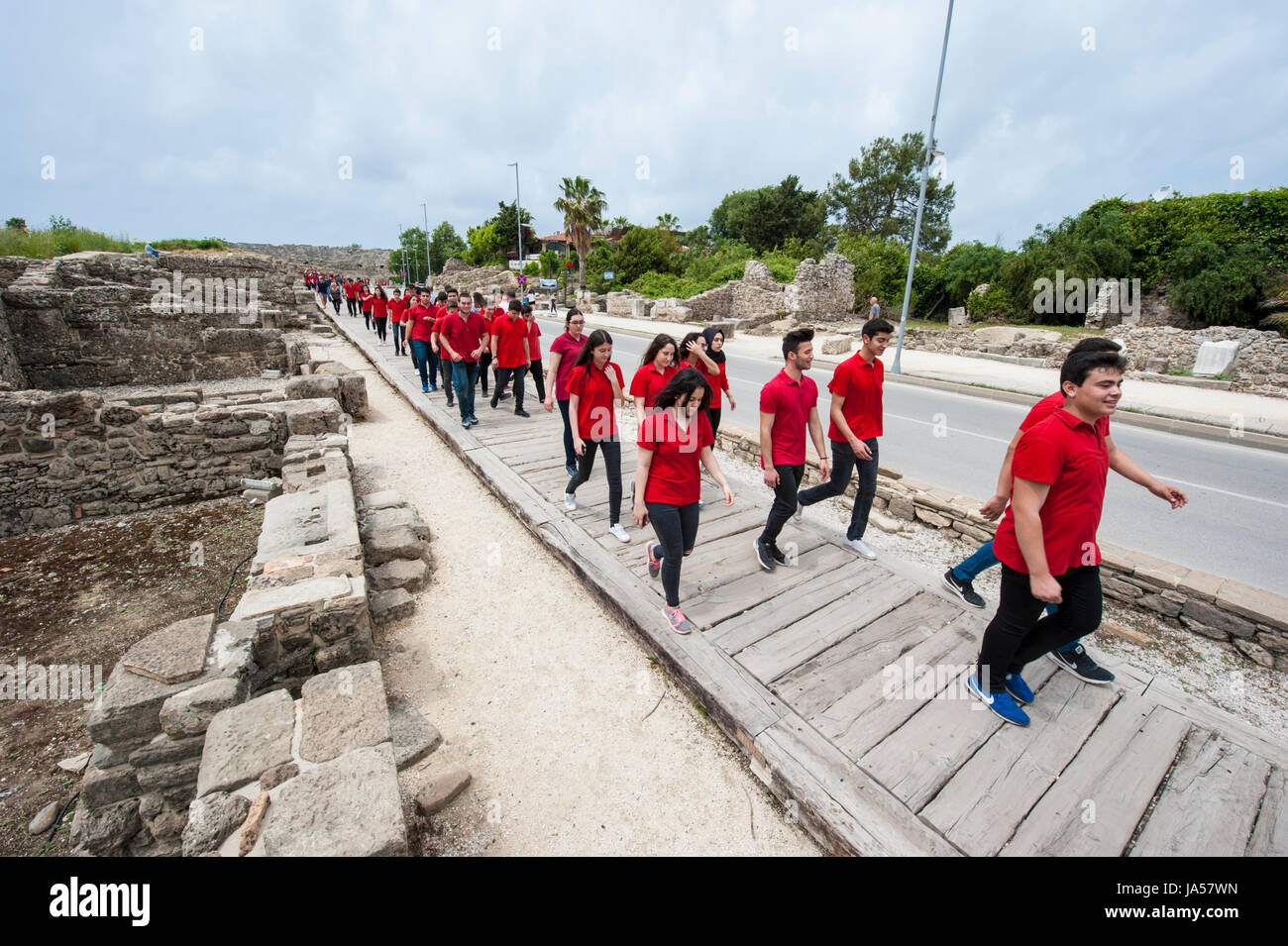 Marching young Turks dressed in red shirts going through antique area in Side, Antalya Province, Turkey. Stock Photo