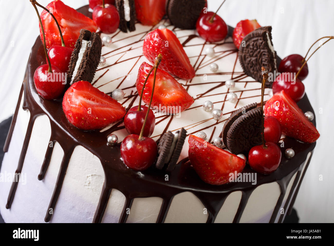 Mousse cake with fresh strawberries and cherries, decorated with biscuits and chocolate close-up. Horizontal Stock Photo
