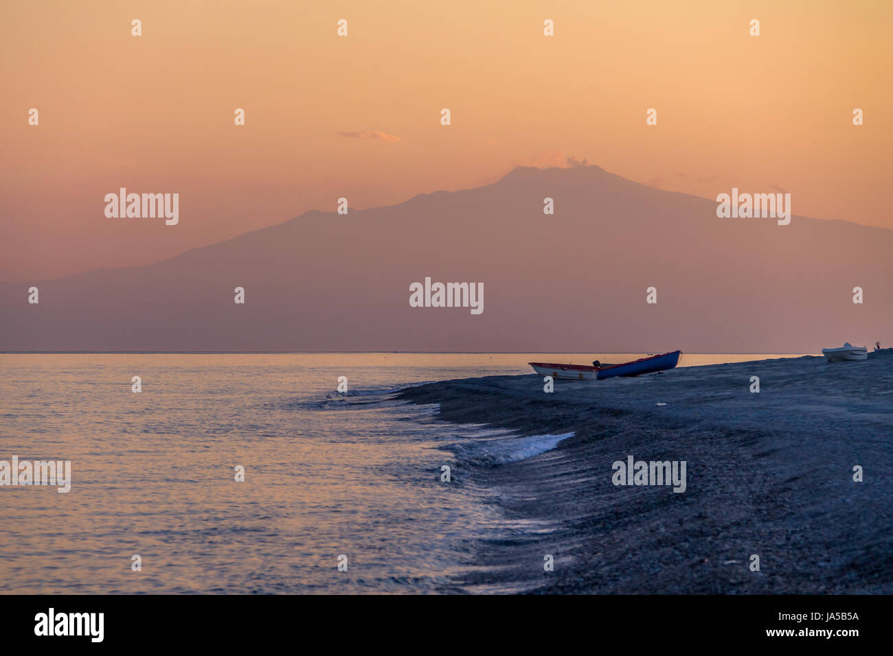 Sunset on a Mediterranean beach of Ionian Sea with Mount Etna Volcano on background - Bova Marina, Calabria, Italy Stock Photo
