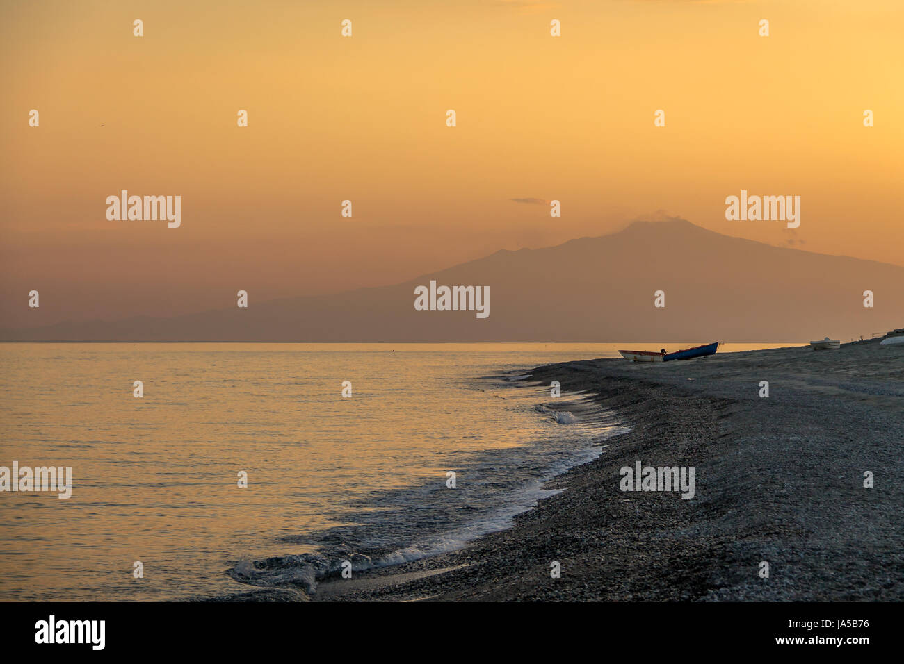 Sunset on a Mediterranean beach of Ionian Sea with Mount Etna Volcano on background - Bova Marina, Calabria, Italy Stock Photo