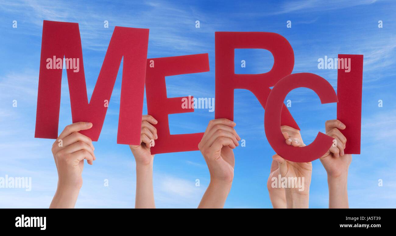 Many Hands Holding the French Word Merci Which Means Thanks in Front of the Sky Stock Photo