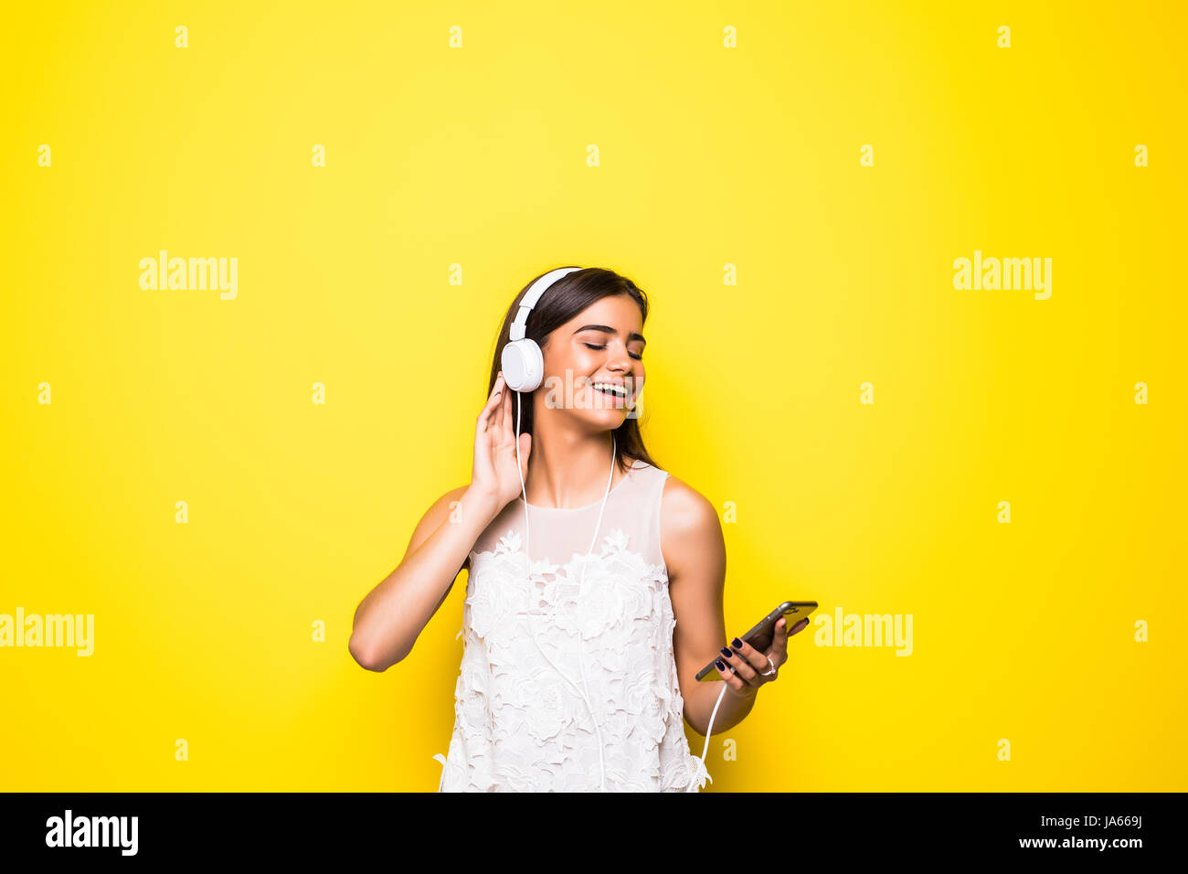 Smiling woman listening music in headphones and using smartphone over ...