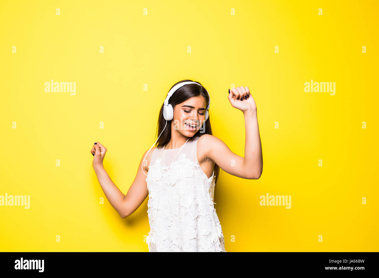 Beautiful young woman in headphones listening to music and dancing on ...