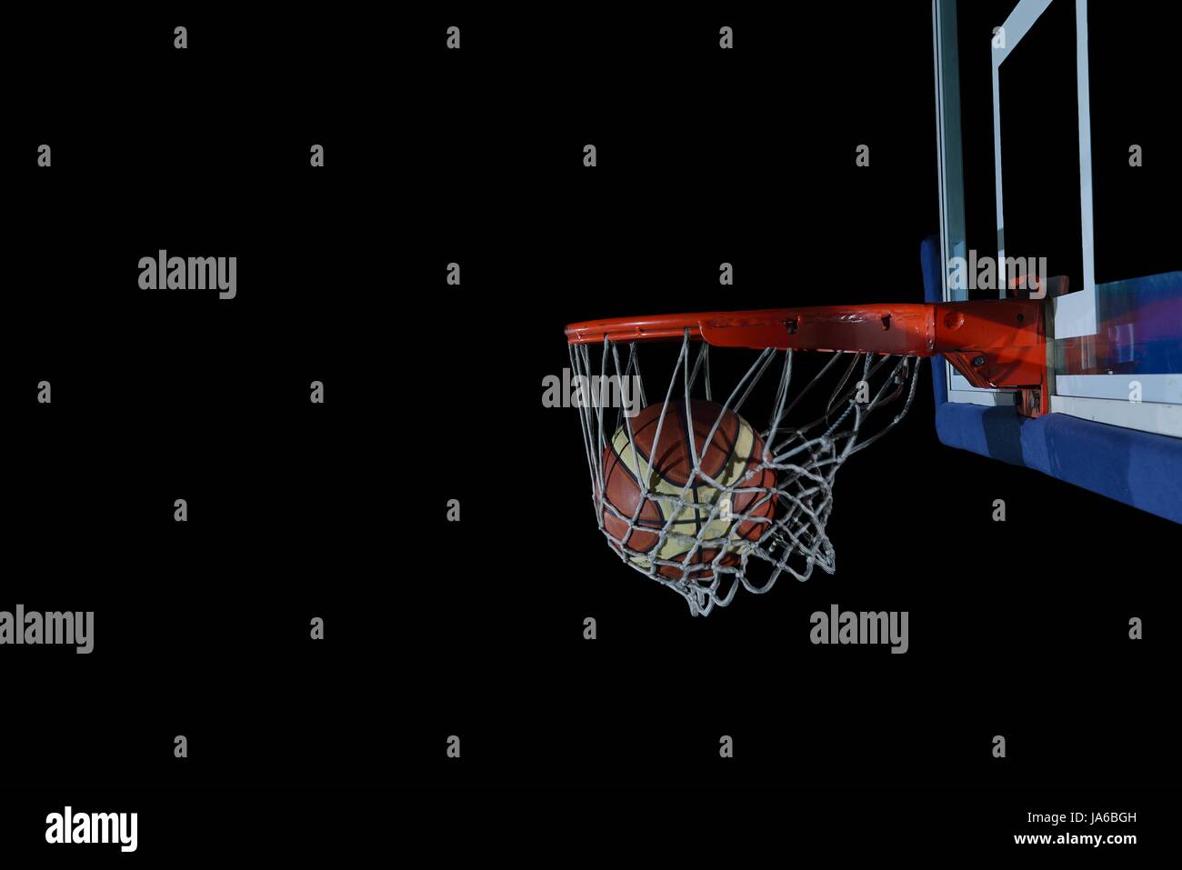 Basketball ball, board and net on black background in gym indoor Stock