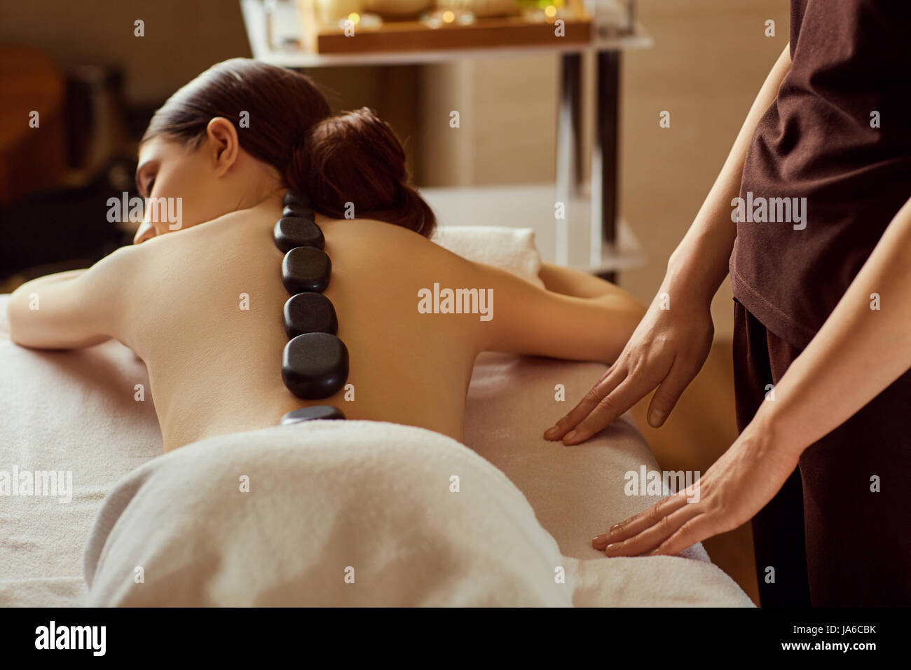 Massage stones on  back of a woman at the spa salon Stock Photo