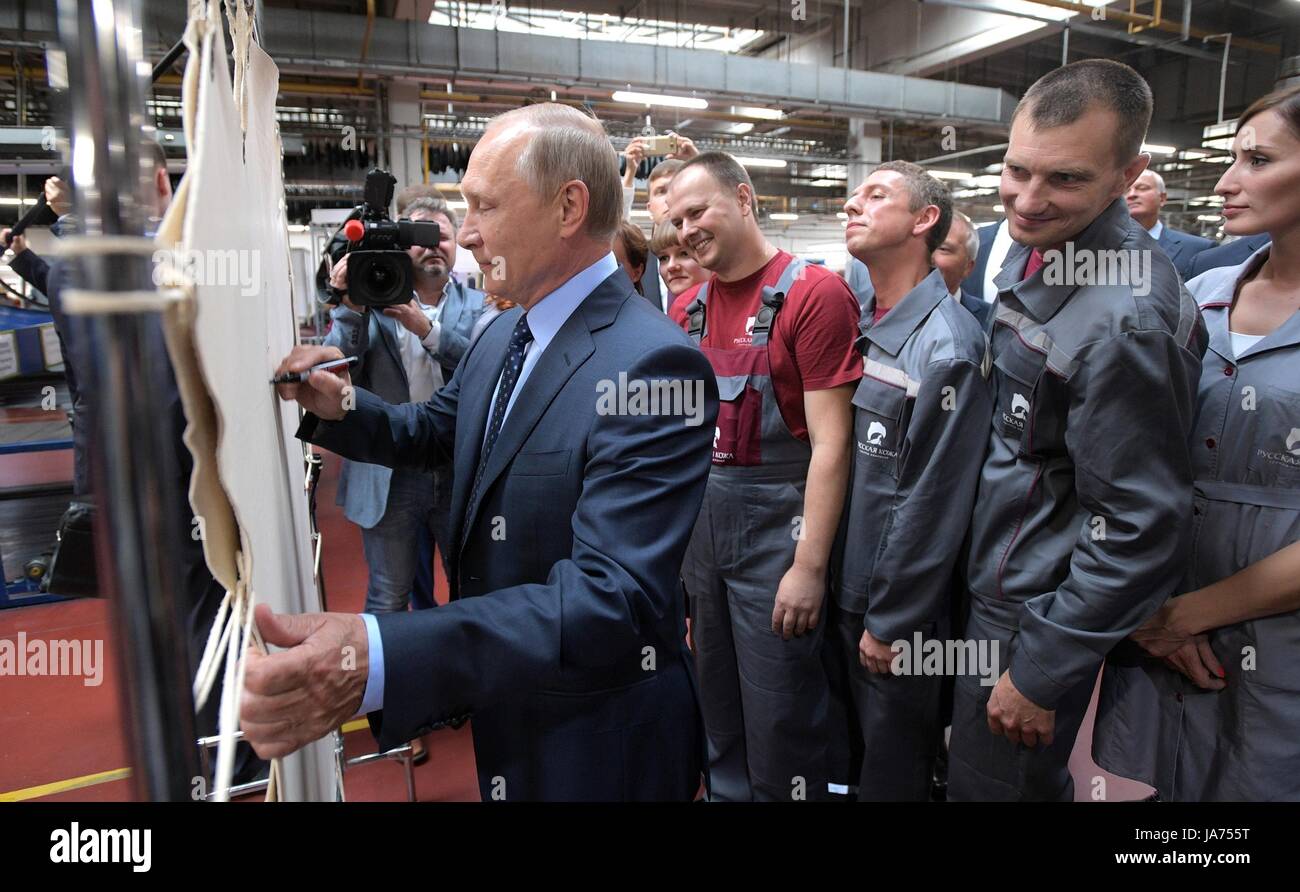 Russian President Vladimir Putin autographs a leather hide as workers look on during a visit to a tannery owned by Russia’s Russkaya Kozha Group August 16, 2017 in Ryazan, Russia. Stock Photo