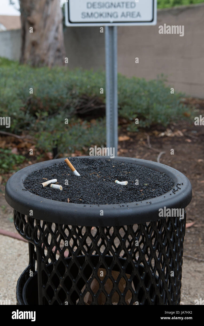An ashtray for smokers and a designated smoking area sign outside a