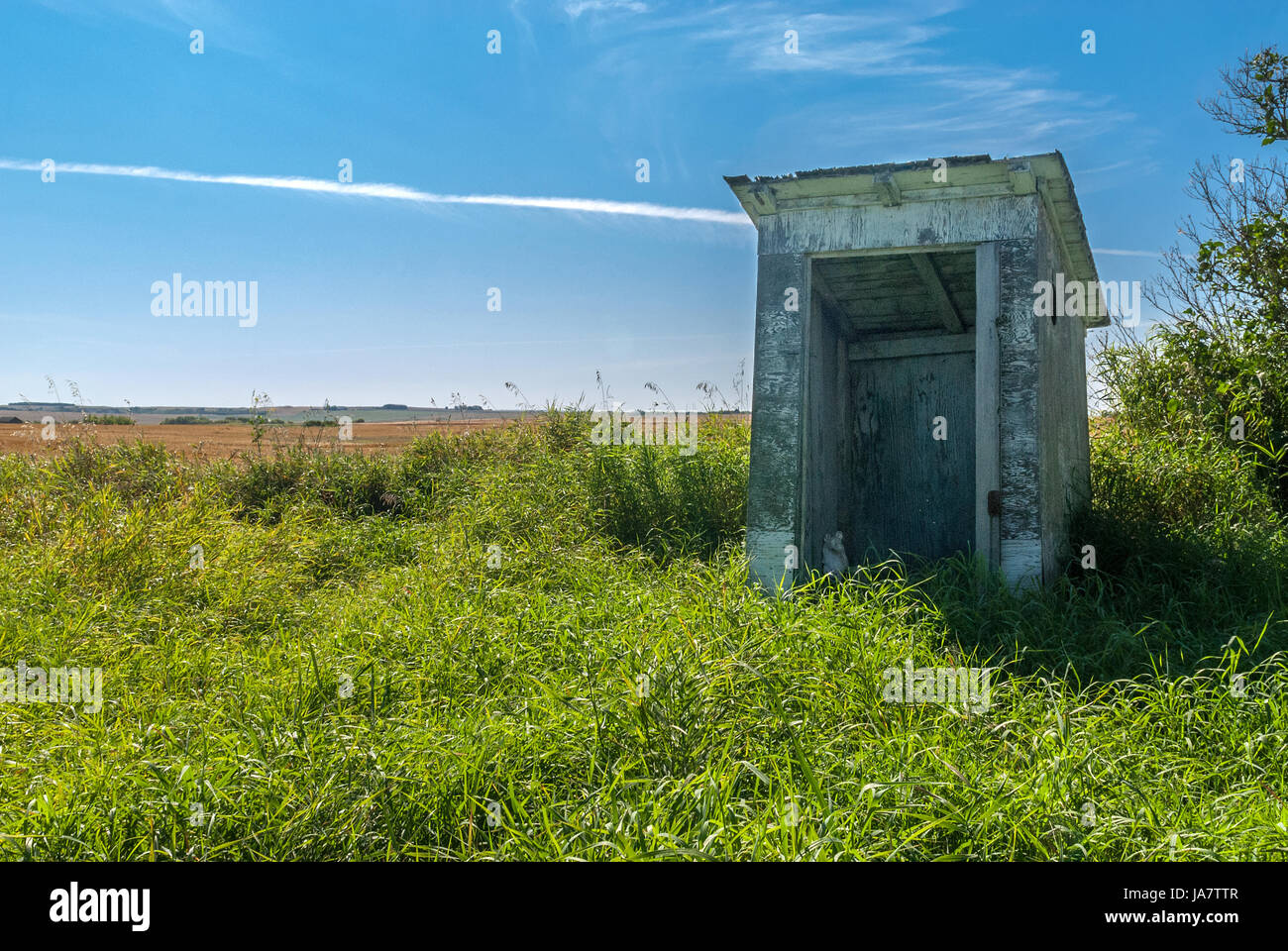 abandoned outhouse in prairie field Stock Photo