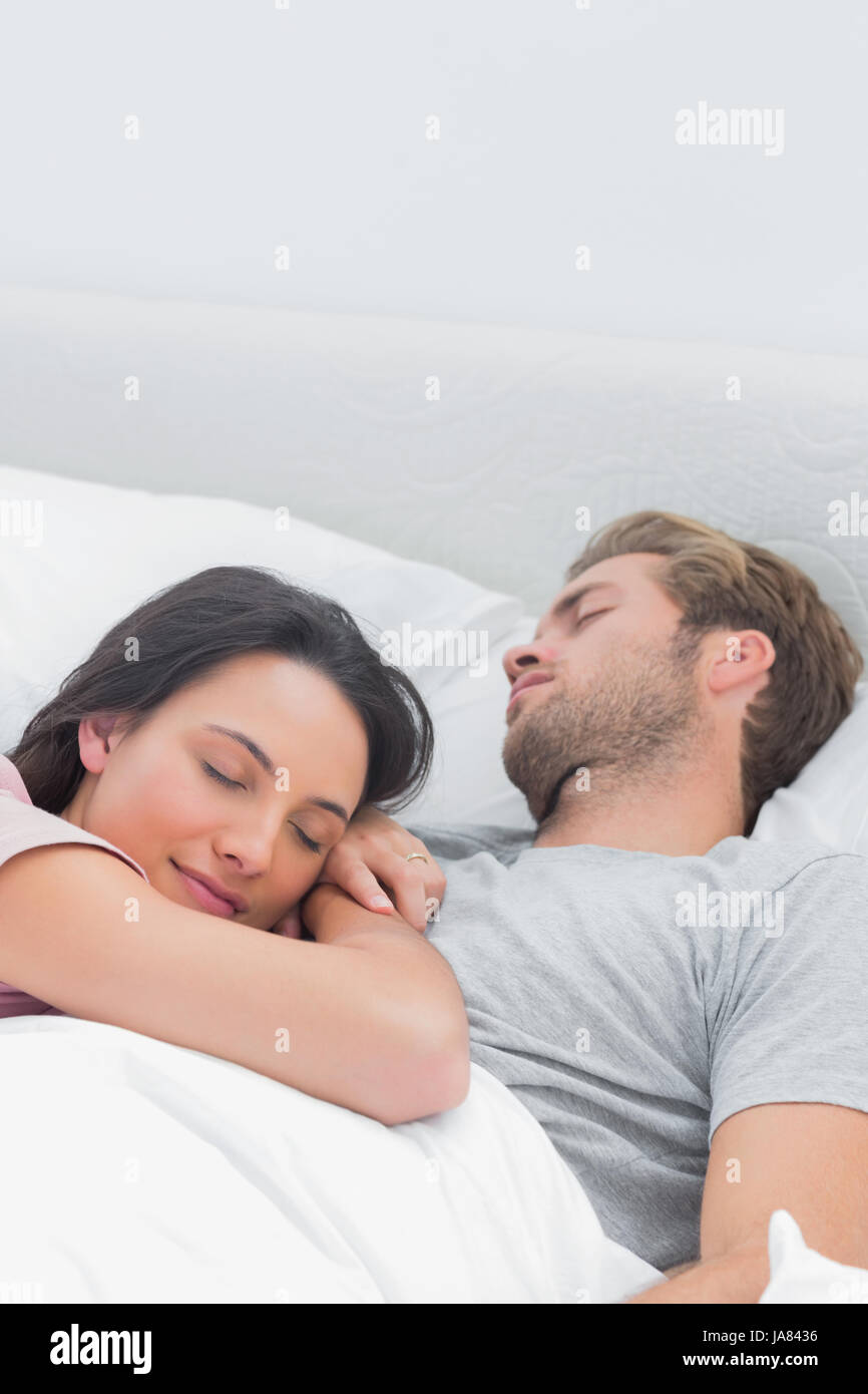 Pretty woman sleeping on her husbands chest in bed Stock Photo Alamy