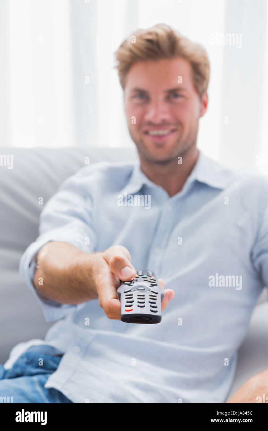 Happy man watching TV in living room and using remote Stock Photo