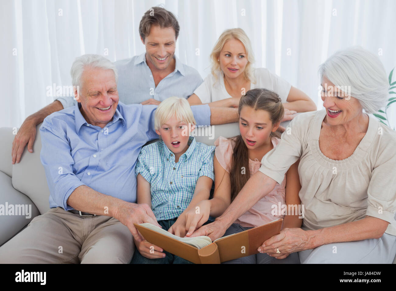 Extended family looking at their album photo in the living room Stock