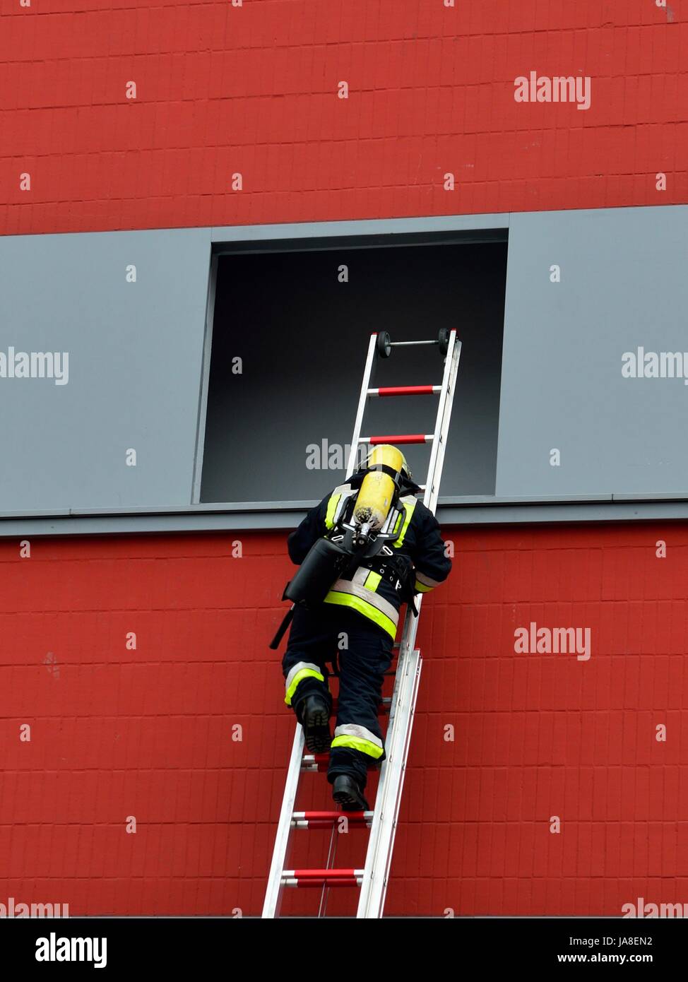 Feuerwehr: Retten, Bergen, Schützen Feuerwehrmann mit Leiter beim einsteigen in eine Fensteröffnung zur Rettung von Menschen Stock Photo