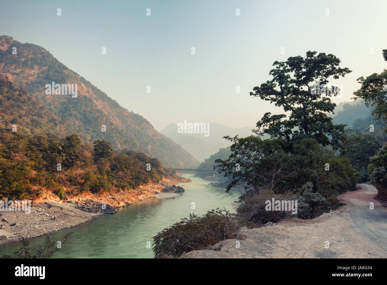 Evening landscape with a river, mountains and a bridge. India, Rishikesh Stock Photo