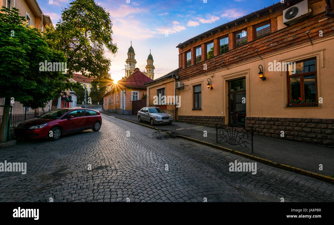 peaceful sunrise in old european town. sun above the roofs on empty street to Cathedral Stock Photo