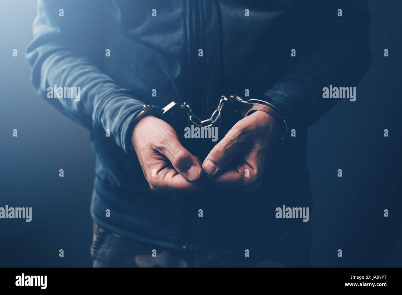 Arrested computer hacker and cyber criminal with handcuffs, close up of hands Stock Photo