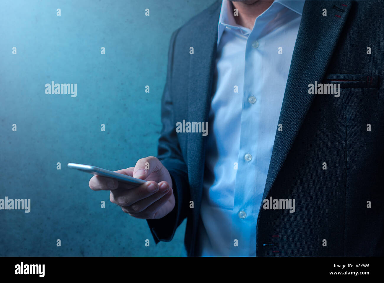 Handsome businessman in modern business suit using mobile phone for everyday job tasks, communication, e-mail correspondence and newsletter reading Stock Photo