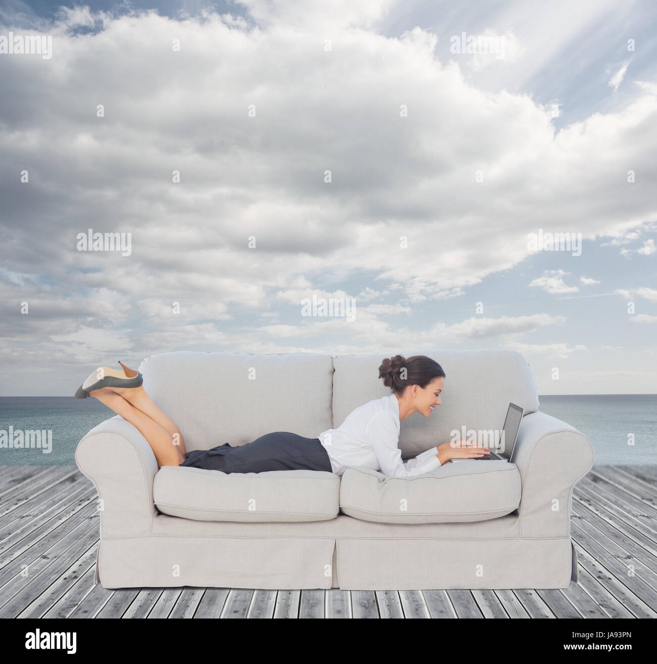 Businesswoman lying on couch and using her laptop Stock Photo - Alamy
