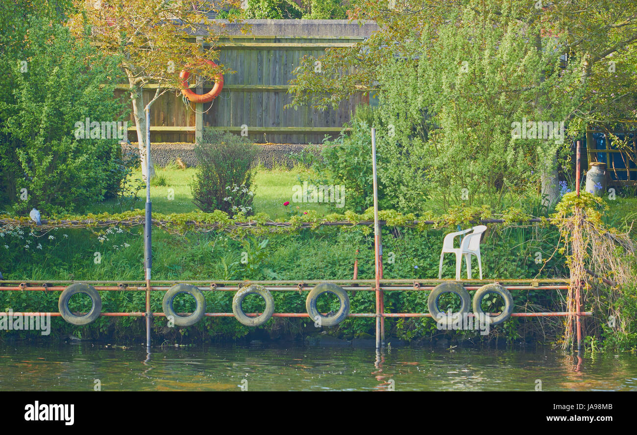 Tranquil scene with plastic chair on scaffolding platform by water and surrounded by nature Stock Photo