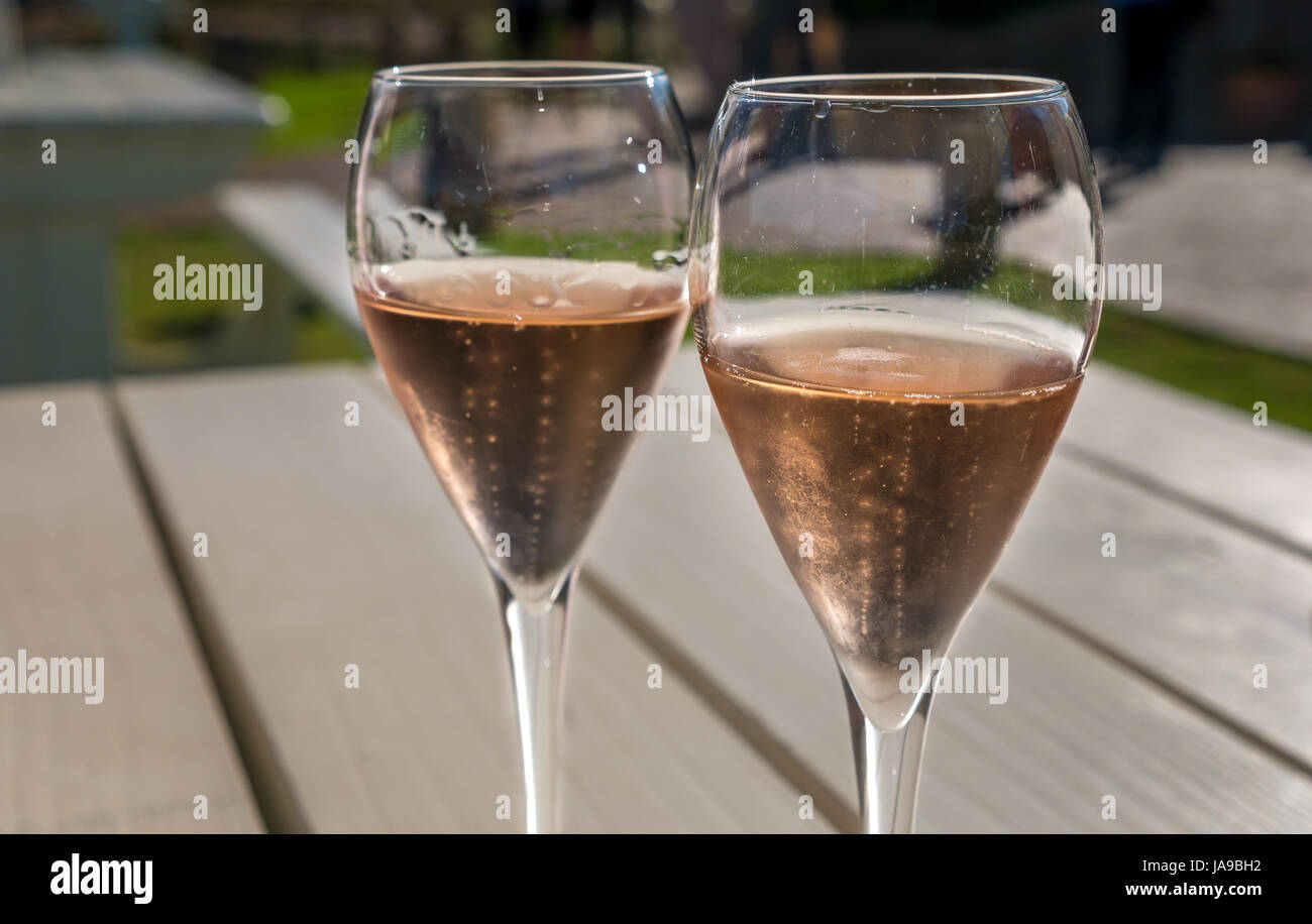 Pair of wine glasses with pink fizzy Rosé wine on sunny outdoor table Stock Photo