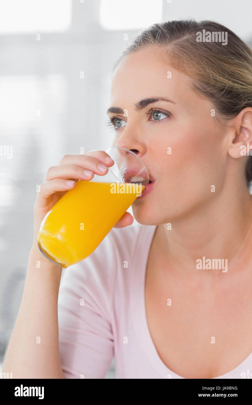 Thoughtful woman drinking orange juice in her kitchen Stock Photo Alamy