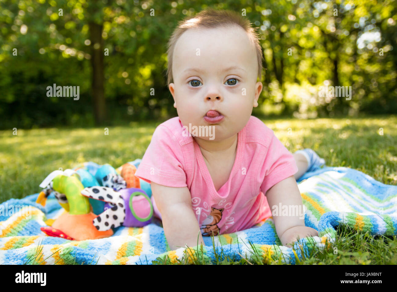 Portrait of Cute baby boy with Down syndrome lying on blanket in summer