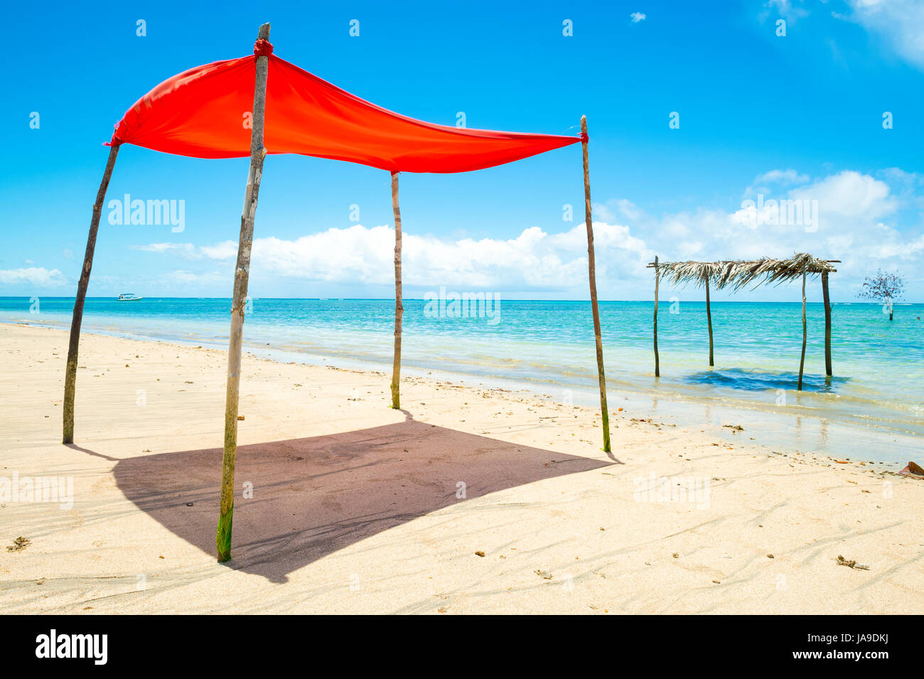Rustic sun shade made from a sheet strung from sticks stands on an empty beach in Bahia, Brazil Stock Photo