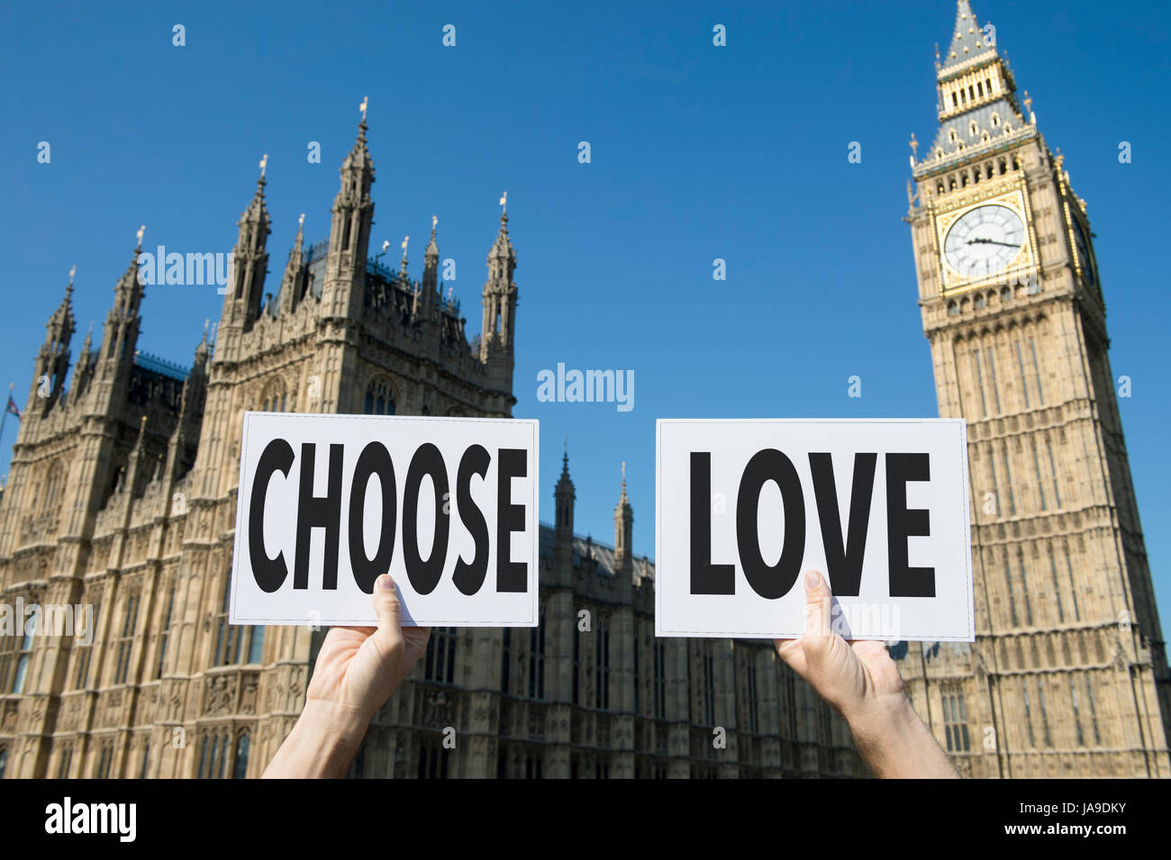 Hands holding up political signboards with the message Choose Love in front of Houses of Parliament at Westminster Palace in London, UK Stock Photo