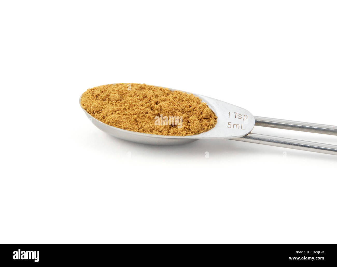 Ground cumin measured in a metal teaspoon, isolated on a white