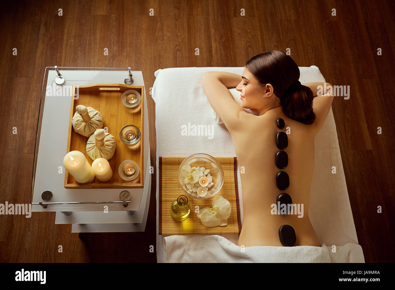 Massage stones on  back of a woman at the spa salon Stock Photo