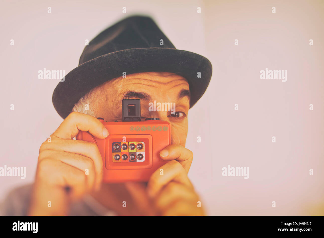 man wearing a trilby hat taking a picture with a Lomography Oktomat plastic camera Stock Photo